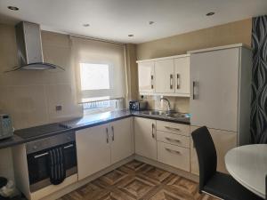a kitchen with white cabinets and a sink and a table at Belfast Luxury Apartment in Belfast