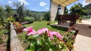 einen Garten mit rosa Blumen und einer Bank in der Unterkunft CASA ROBY in Follina