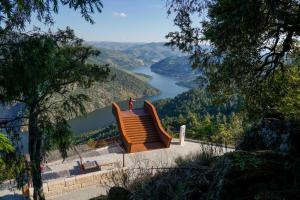 eine Person, die auf einer Bank mit Blick auf einen See steht in der Unterkunft Hotel Ribadouro in Alijó