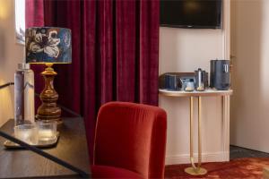 une chambre avec une chaise rouge et une table avec une lampe dans l'établissement Hôtel L de Lutèce, à Paris