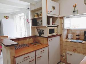 uma pequena cozinha com armários brancos e um micro-ondas em Gencay La maison blanche em Gençay