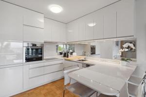 a white kitchen with white cabinets and a table at Tourelle - Appartement moderne dans le centre de Genève in Geneva