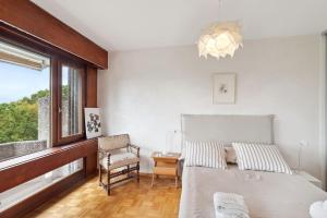 Tourelle - Appartement moderne dans le centre de Genève في جنيف: غرفة نوم بسرير وكرسي ونافذة
