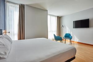 a bedroom with a bed and two chairs and a tv at Silken Sant Gervasi in Barcelona