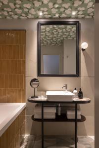 a bathroom with a sink and a mirror and a tub at H&ocirc;tel L de Lut&egrave;ce in Paris