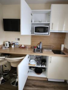 cocina con armarios blancos y microondas en Lovely Private Room en Dublín