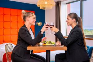 two women sitting at a table with glasses of wine at Le Green des Impressionnistes - Cergy-Pontoise in Pontoise +48 photos