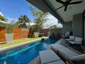 a swimming pool with lounge chairs next to a fence at La Mer Luxury Private Pool Villa in Pantai Cenang