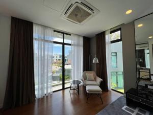 a living room with a chair and large windows at La Mer Luxury Private Pool Villa in Pantai Cenang