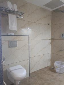 baño con aseo y puerta de ducha de cristal en SIGNATURE INN, en Chikmagalur