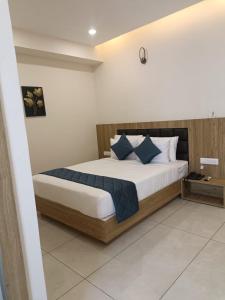 1 dormitorio con 1 cama grande con almohadas azules en SIGNATURE INN, en Chikmagalur