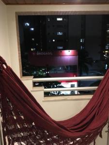 a hammock in front of a window with a view of a city at Poucos passos do mar na Praia da Costa in Vila Velha +19 photos
