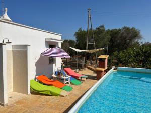 een zwembad met stoelen en een parasol naast een huis bij Chateaux des Trulli in San Michele Salentino