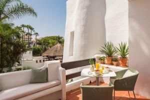 a balcony with a couch and a table and chairs at 2-Bedroom Apartment in Puente Romano, Marbella in Marbella