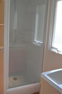 a shower with a glass door next to a sink at camping Le moulin in Patornay