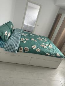 a bed with a green blanket with flowers on it at IN APART HOTEL in Bucharest