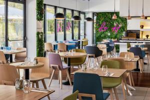 un restaurante con mesas, sillas y ventanas en Holiday Inn - Marseille Airport, an IHG Hotel en Vitrolles