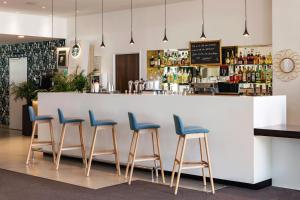 a bar with four blue stools in front of a counter at Holiday Inn - Marseille Airport, an IHG Hotel in Vitrolles