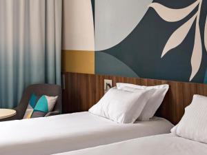 ヴィトロルにあるゴールデン チューリップ マルセイユ エアポートのベッド2台とテーブルが備わるホテルルームです。
