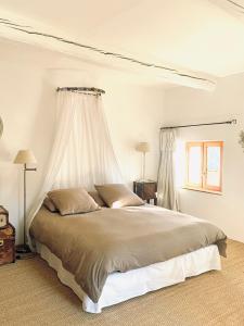 a white bedroom with a bed with a canopy at La Bousquetière in Jausiers