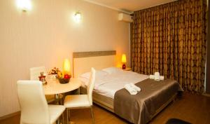 een hotelkamer met een bed en een tafel en stoelen bij Royal Apartments in Batoemi