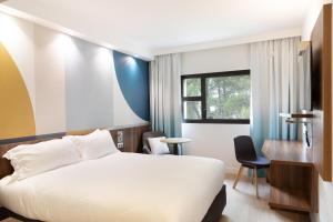 ein Hotelzimmer mit einem weißen Bett und einem Schreibtisch in der Unterkunft Holiday Inn - Marseille Airport, an IHG Hotel in Vitrolles