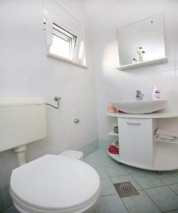a white bathroom with a toilet and a sink at House Lavanda in Premuda