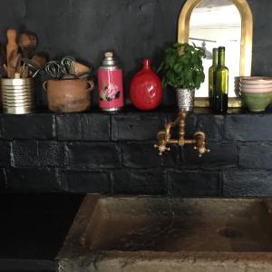 a brick counter with a sink and a mirror at La Bousquetière in Jausiers