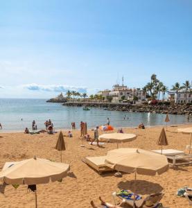 a group of people on a beach with umbrellas at OMBÚLAFUENTE in Puerto de Mogán +9 photos