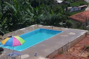 a swimming pool with a colorful umbrella next to it at Sítio da Serra em Ouro Preto MG in Cachoeira do Campo