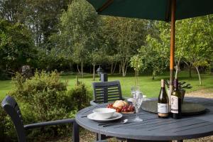 a table with a plate of food and bottles of wine at Alpaca Lodge in Burford