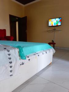 Cama en habitación con TV en la pared en Kigali Peace villa, en Kigali