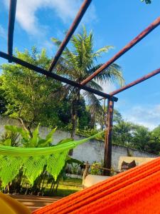 a hammock with a palm tree in the background at SITIO RECANTO DOS PASSAROS in Itacaré