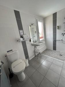 La salle de bains blanche est pourvue de toilettes et d'un lavabo. dans l'établissement Logis Cris Hôtel, Lyon Est, à Corbas