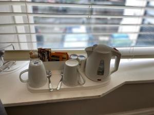 a white coffee pot and cups on a counter next to a window at The Unicorn, Ambleside in Ambleside