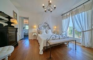 a white bedroom with a bed and a chandelier at VILLA MERCEDES 300 m de la plage in La Londe-les-Maures