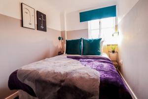 a bedroom with a bed with green pillows and a window at Modern 2BR Apartment in the heart of East London, Fast Internet & Close To Shops in London