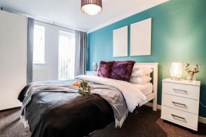 a bedroom with a bed and a blue wall at Modern 2BR Apartment in the heart of East London, Fast Internet & Close To Shops in London