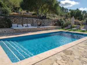 a swimming pool with chairs and a stone wall at Preciosa casa familiar cerca Esporlas Na Servera in Esporles