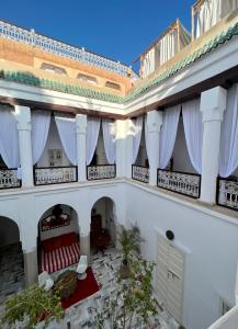 a large white building with windows and red chairs at Riad Tizwa Marrakech in Marrakesh