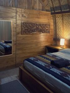 two beds in a room with wooden walls at Besakih Homestay & Villa in Besakih