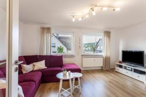 a living room with a purple couch and a tv at Ferienwohnung Grübel in Kirchhundem