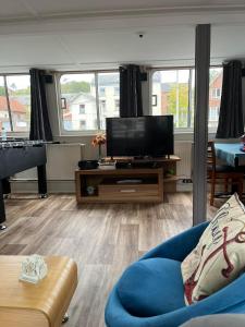 a living room with a tv and a blue couch at Gîte Le Sambre in Thuin