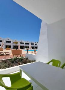 een kamer met een witte tafel en groene stoelen bij Sands Beach - Hoy Hotels in Costa Teguise