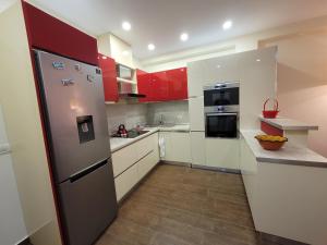 eine Küche mit roten Schränken und einem Kühlschrank aus Edelstahl in der Unterkunft Spacious and Cozy Apartment in Tirana