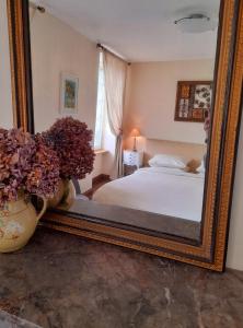 a mirror in a bedroom with a bed and flowers at Domfront - Numero CINQ in Domfront