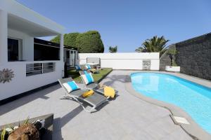 a swimming pool with lounge chairs and a house at Casa Nublo - 3 Bedroom family villa - Great sea views from rooftop terrace in Puerto Calero