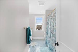 a bathroom with a shower with a blue shower curtain at Sandy Clydesdale: Sagamore Beach Sandwich in Sandwich +41 photos