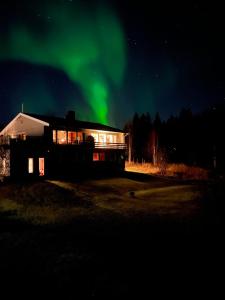a house with the aurora in the sky behind it at Marta's Home-cozy appartment near the Airport in Andselv