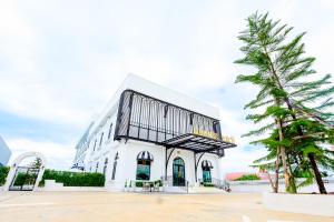Un edificio blanco con un árbol delante. en Marble Arch De Loei Hotel, en Loei